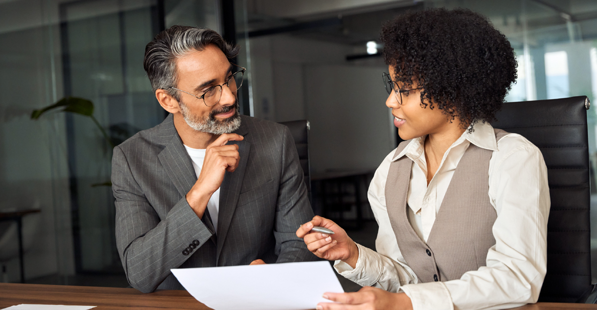 decorative image of a man and woman sitting behind papers that need to be signed
