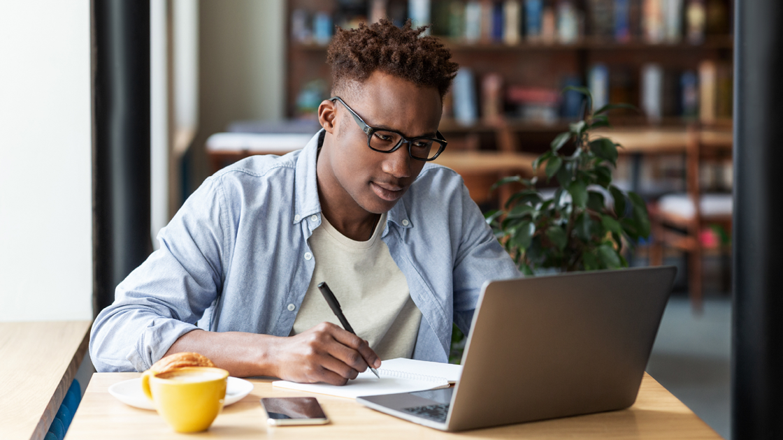 decorative image of a person in front of a laptop and holding a pen and paper