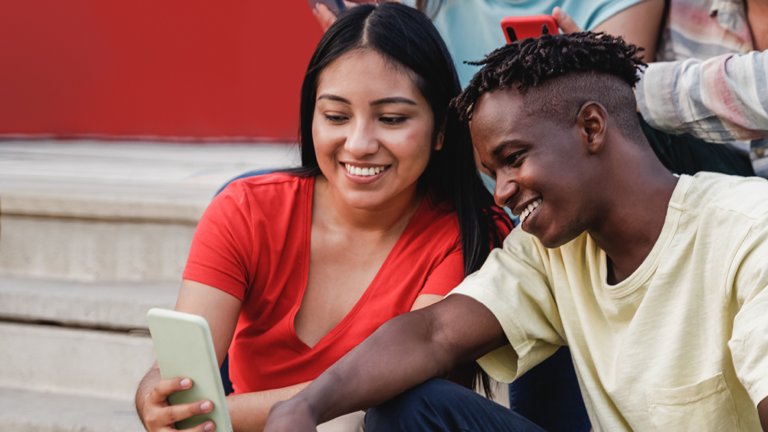 decorative image of an indigenous person looking at her phone while hanging out with a friend
