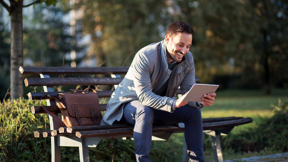 decorative image of a man sitting on a park bench looking at a device