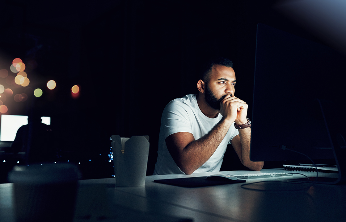 man sitting at a desk looking at a screen in the dark