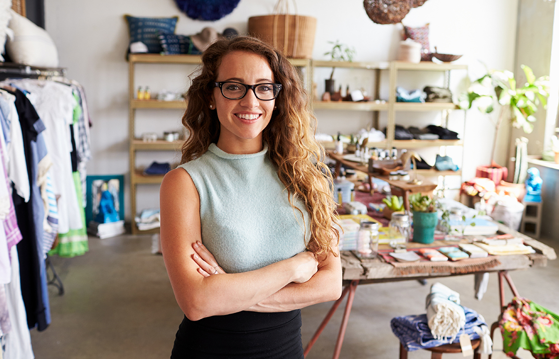 woman standing with arms crossed and wearing glasses in a store